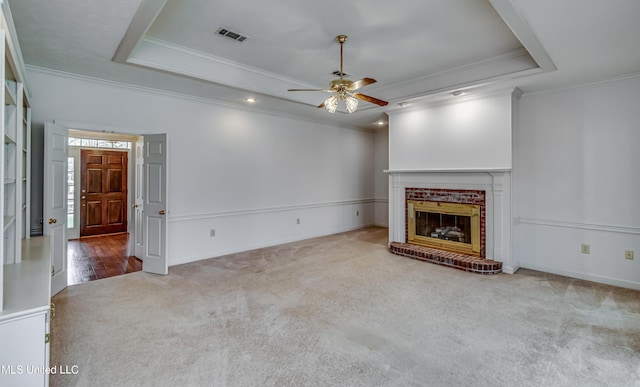 unfurnished living room with visible vents, a fireplace, a tray ceiling, and carpet flooring