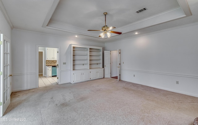 unfurnished bedroom with crown molding, a tray ceiling, visible vents, and light colored carpet