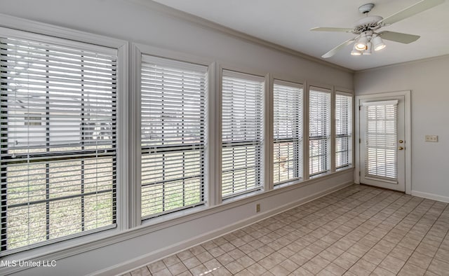 empty room featuring ceiling fan, baseboards, and crown molding