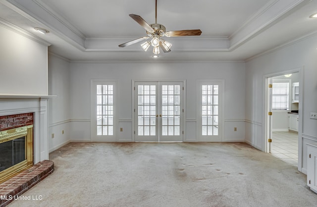 unfurnished living room with carpet floors, french doors, a brick fireplace, and a raised ceiling