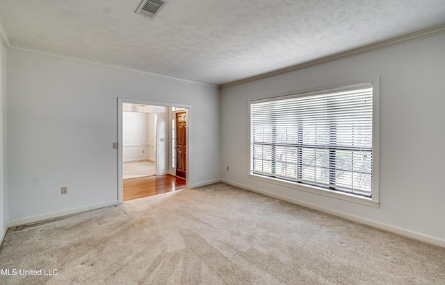 carpeted spare room with ornamental molding, visible vents, a textured ceiling, and baseboards