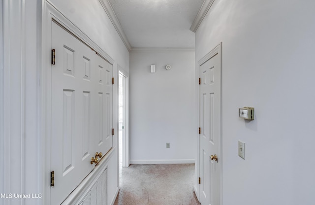 hall featuring baseboards, ornamental molding, and light colored carpet