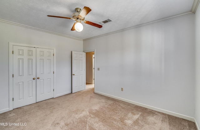 unfurnished bedroom with ornamental molding, a closet, visible vents, and carpet floors