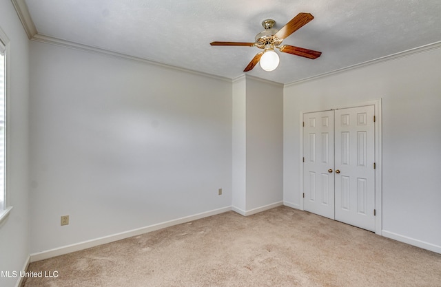 unfurnished bedroom with a closet, carpet flooring, crown molding, and baseboards