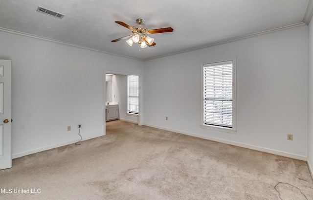 spare room featuring ceiling fan, light colored carpet, visible vents, baseboards, and ornamental molding