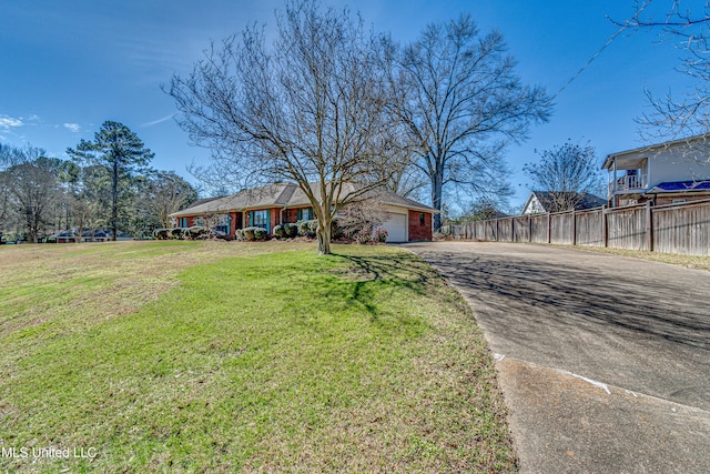 view of front of home featuring aphalt driveway, an attached garage, fence, a front lawn, and brick siding