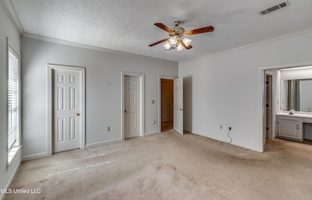 unfurnished bedroom with light colored carpet, a sink, visible vents, baseboards, and crown molding