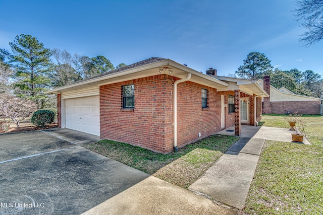 view of front of property featuring brick siding, a chimney, a garage, driveway, and a front lawn