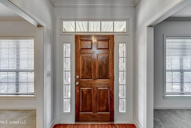 entrance foyer with ornamental molding, carpet, and baseboards