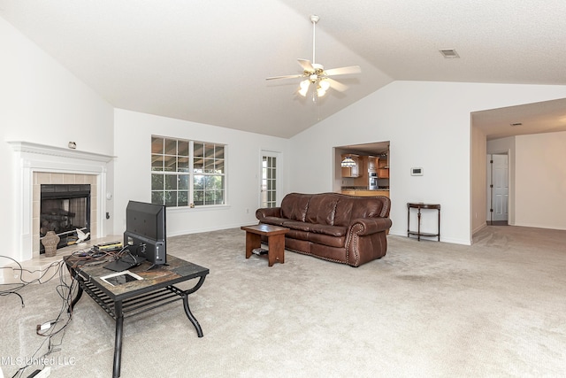 living room with light colored carpet, vaulted ceiling, ceiling fan, and a tiled fireplace