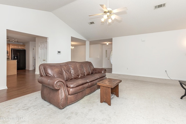 living room featuring carpet, ceiling fan with notable chandelier, and vaulted ceiling