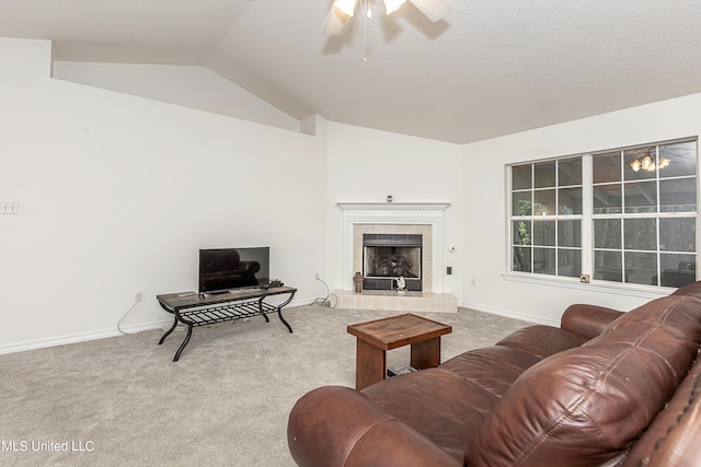 living room featuring ceiling fan, carpet floors, a tile fireplace, and vaulted ceiling