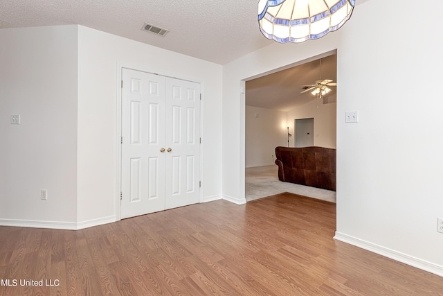 interior space with ceiling fan, light wood-type flooring, a textured ceiling, and lofted ceiling