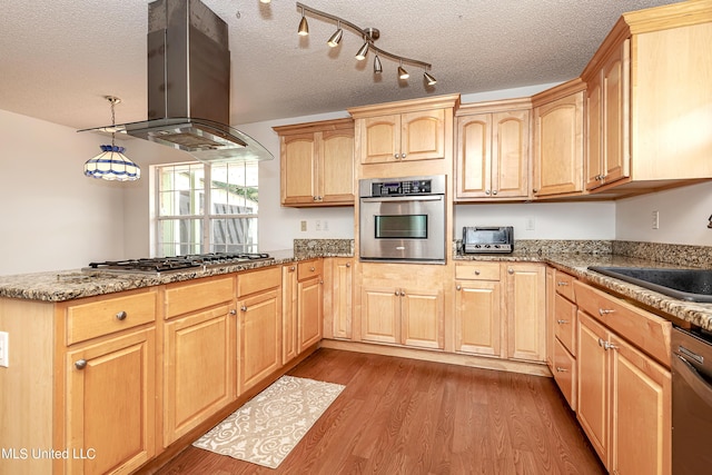 kitchen featuring light brown cabinets, island exhaust hood, a textured ceiling, appliances with stainless steel finishes, and light wood-type flooring