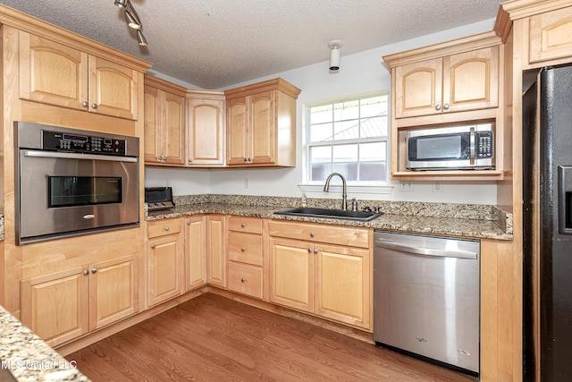 kitchen with light stone counters, sink, light brown cabinets, and appliances with stainless steel finishes