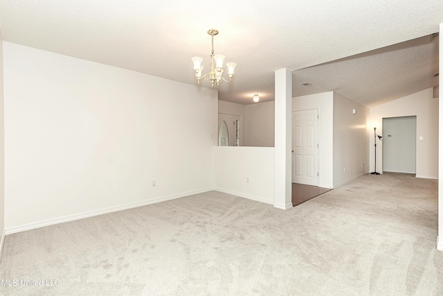 unfurnished room featuring a textured ceiling, carpet floors, a chandelier, and lofted ceiling