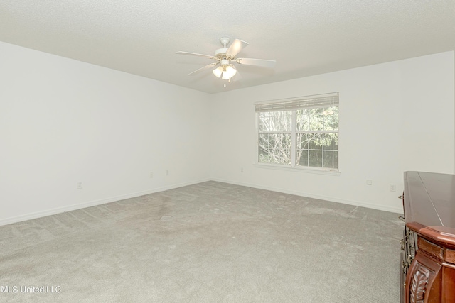 spare room featuring light carpet, a textured ceiling, and ceiling fan