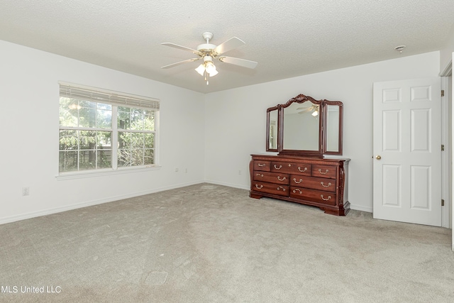 unfurnished bedroom with ceiling fan, light colored carpet, and a textured ceiling