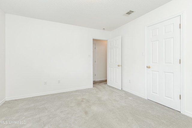 spare room with a textured ceiling and light colored carpet