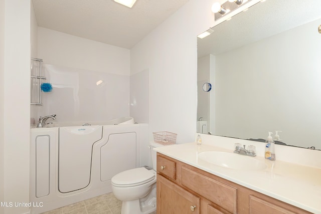 bathroom featuring a bathtub, vanity, a textured ceiling, and toilet