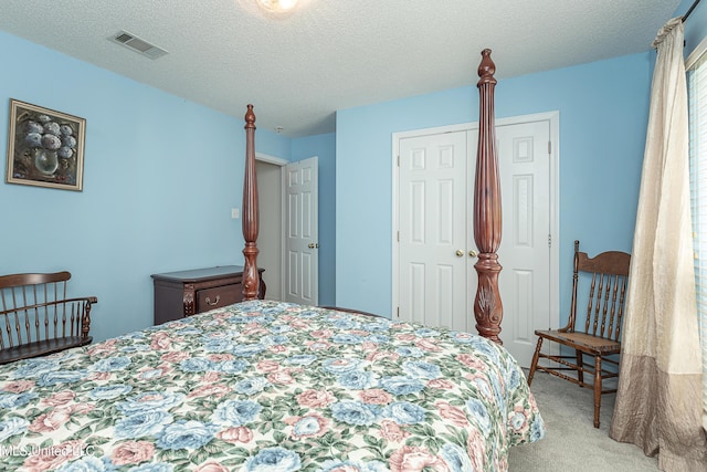 bedroom with a textured ceiling, light colored carpet, and a closet