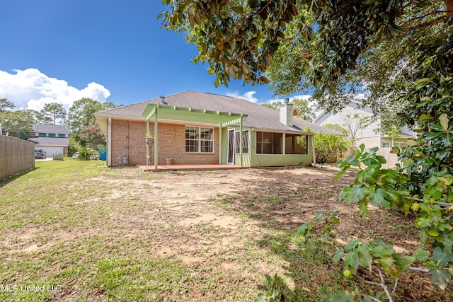 rear view of property featuring a yard, a patio, and a sunroom