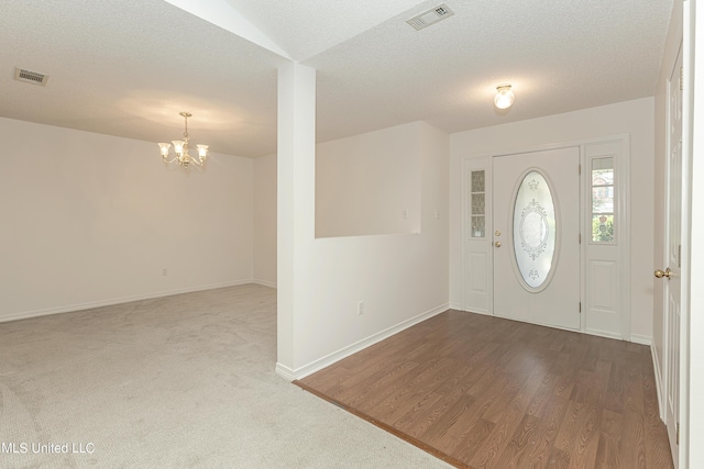 entrance foyer featuring a textured ceiling, hardwood / wood-style flooring, and a notable chandelier