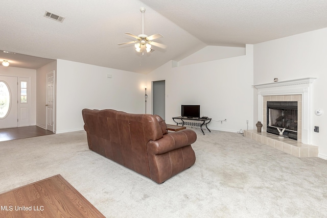 carpeted living room featuring a textured ceiling, ceiling fan, a fireplace, and vaulted ceiling