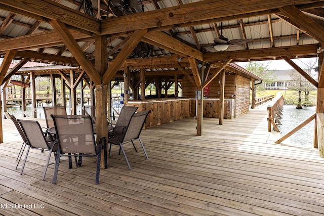 wooden deck with outdoor dining area, a water view, and a ceiling fan