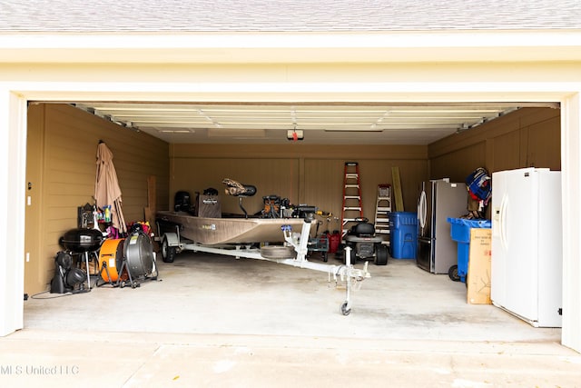 garage featuring freestanding refrigerator, white fridge with ice dispenser, and a garage door opener