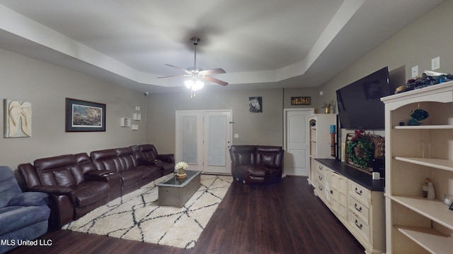 living room featuring ceiling fan, a tray ceiling, and dark hardwood / wood-style flooring