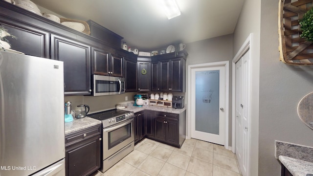 kitchen with light stone countertops, stainless steel appliances, and light tile patterned floors