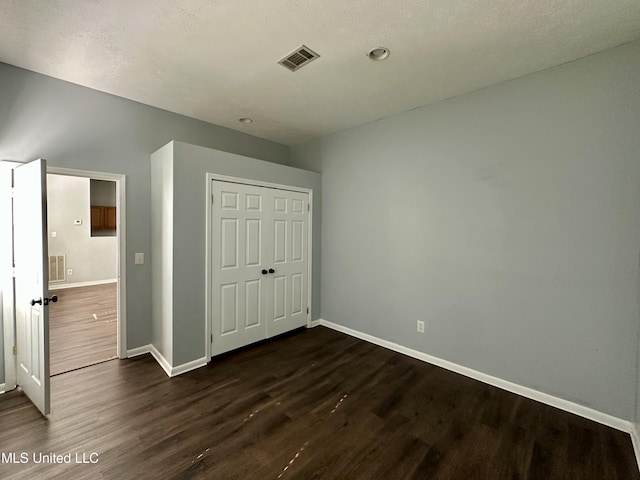 unfurnished bedroom featuring dark hardwood / wood-style floors and a closet