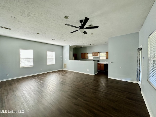 unfurnished living room with a textured ceiling, dark hardwood / wood-style flooring, and ceiling fan