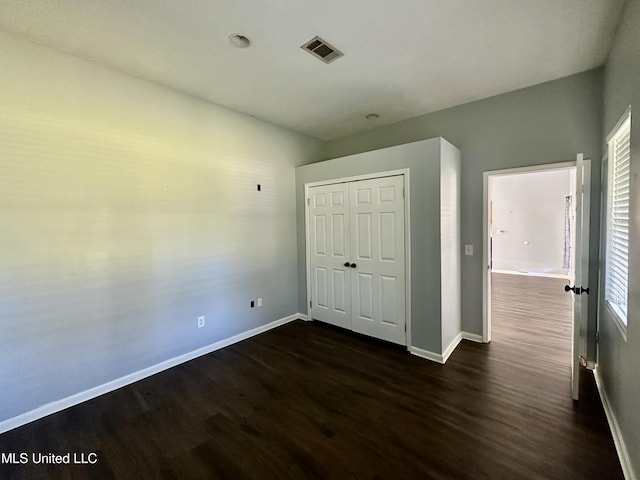 unfurnished bedroom with dark hardwood / wood-style flooring and a closet