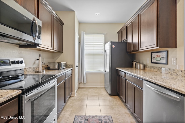 15035 Baylor Ave, Gulfport, MS 39503 - kitchen with appliances with stainless steel finishes, dark brown cabinetry, light tile patterned floors, light stone countertops, and baseboards