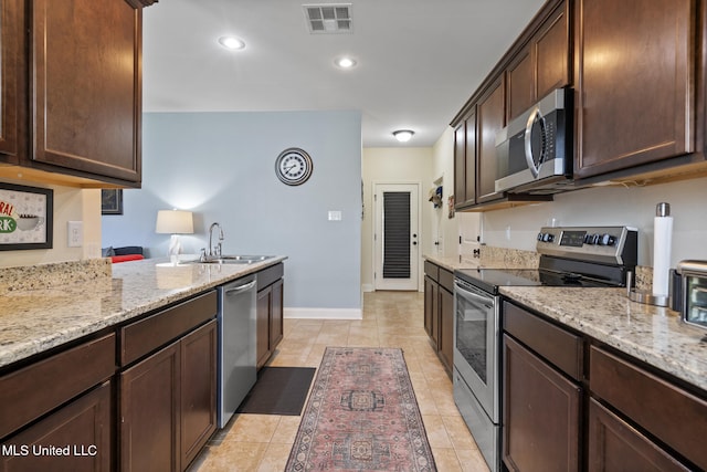 15035 Baylor Ave, Gulfport, MS 39503 - kitchen featuring stainless steel appliances, a sink, dark brown cabinetry, light stone countertops, and recessed lighting