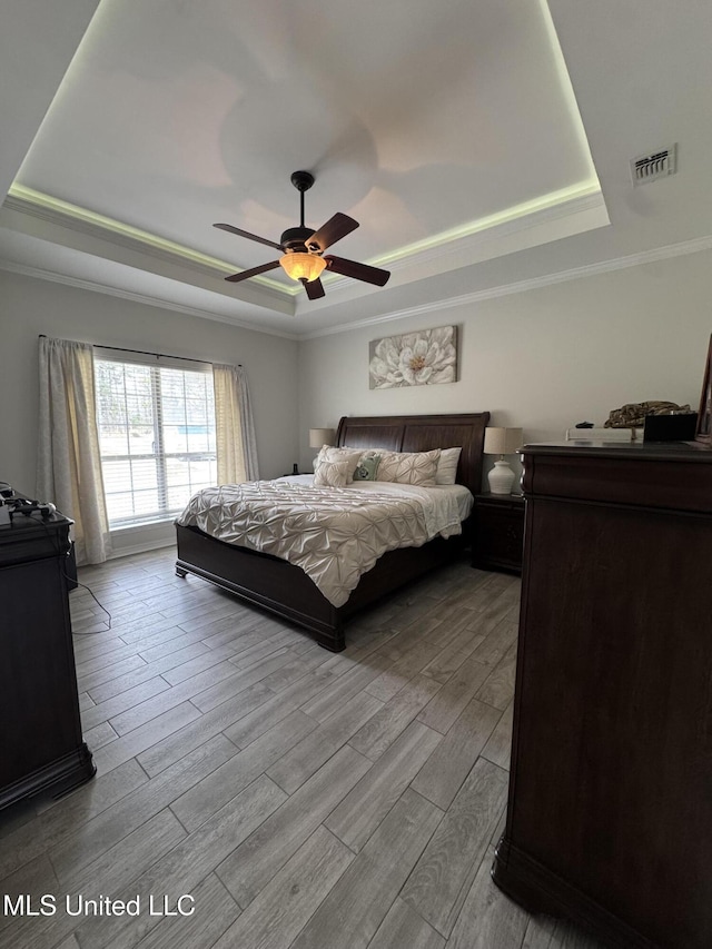 bedroom featuring wood finished floors, a raised ceiling, and visible vents