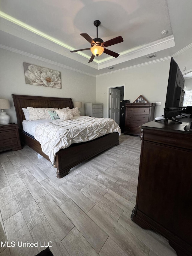 bedroom with ceiling fan, visible vents, ornamental molding, wood tiled floor, and a tray ceiling