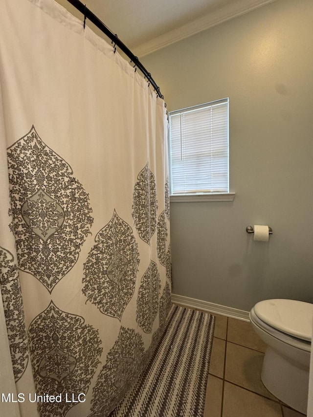 bathroom featuring toilet, a shower with shower curtain, baseboards, ornamental molding, and tile patterned floors