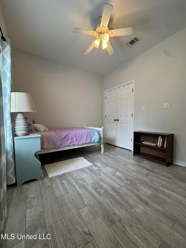 bedroom with a ceiling fan, a closet, visible vents, and wood finished floors