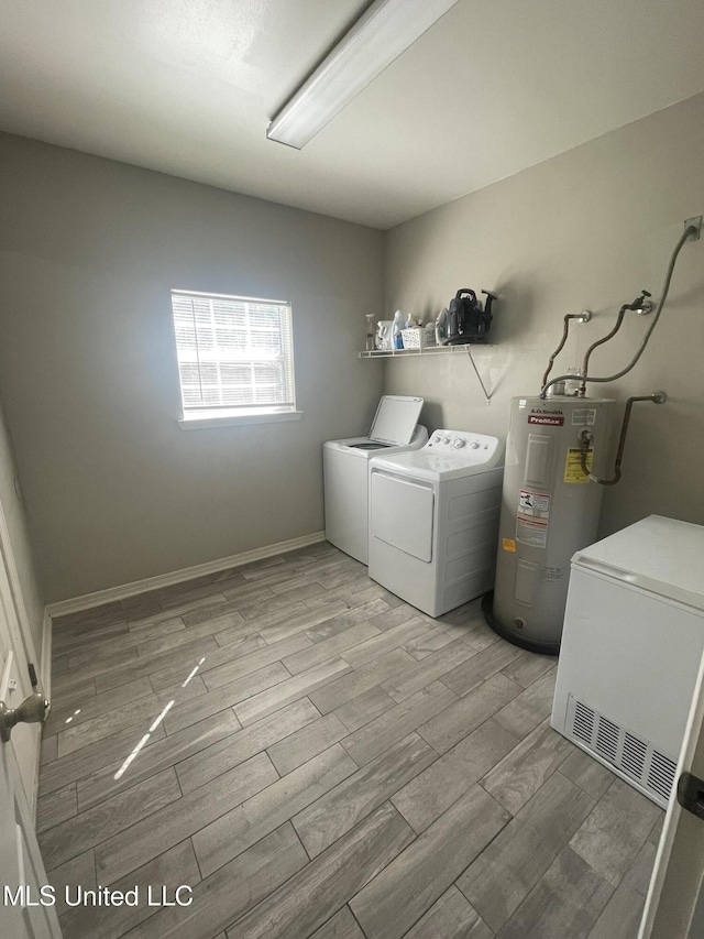 laundry area featuring electric water heater, laundry area, baseboards, washer and dryer, and wood tiled floor