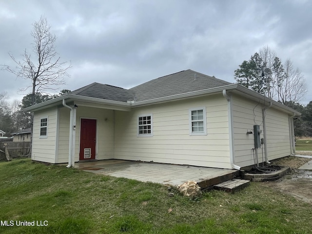 back of property with roof with shingles, a lawn, a patio area, and fence