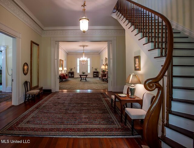 hall with hardwood / wood-style flooring, ornamental molding, and a chandelier