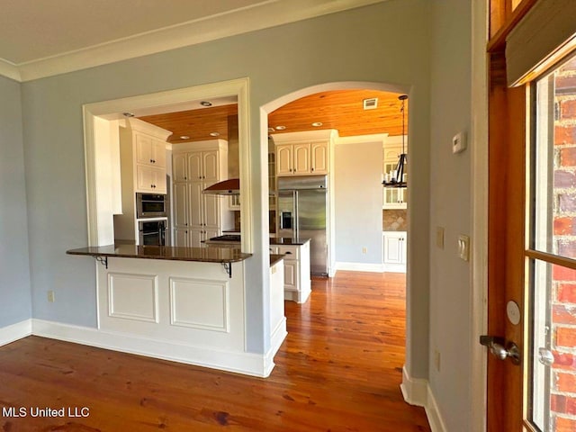 162 Lake Ridge Dr, Madison, MS 39110 - kitchen featuring arched walkways, dark countertops, wood finished floors, a peninsula, and ornamental molding