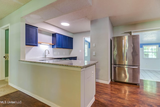 3217 N 2nd St, Ocean Springs, MS 39564 - kitchen with freestanding refrigerator, blue cabinets, light stone countertops, a sink, and a peninsula