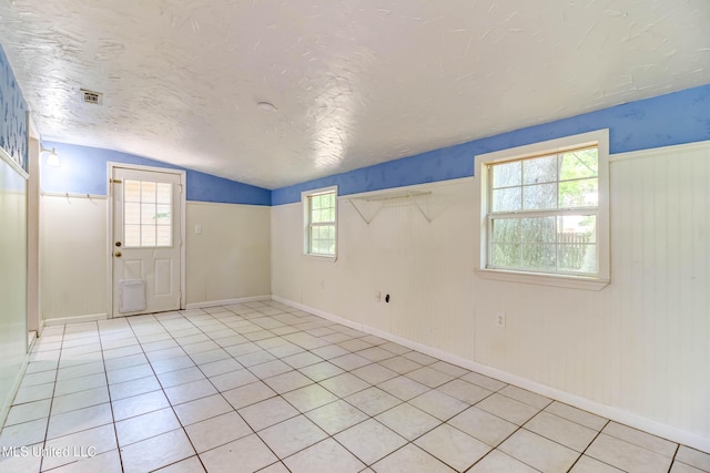 3217 N 2nd St, Ocean Springs, MS 39564 - unfurnished room featuring lofted ceiling, a textured ceiling, light tile patterned flooring, and baseboards