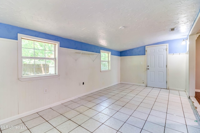 3217 N 2nd St, Ocean Springs, MS 39564 - spare room with lofted ceiling, a textured ceiling, light tile patterned flooring, and baseboards