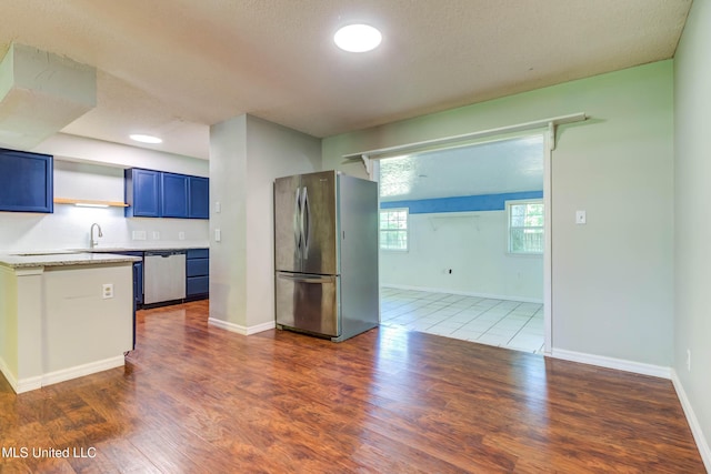 3217 N 2nd St, Ocean Springs, MS 39564 - kitchen with appliances with stainless steel finishes, light countertops, wood finished floors, blue cabinetry, and baseboards