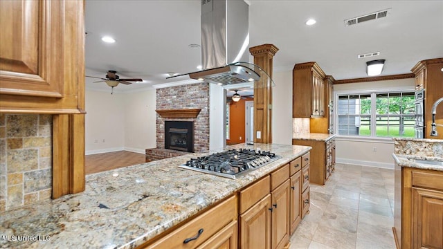 112 Eastgate Cir, Forest, MS 39074 - kitchen featuring ceiling fan, stainless steel gas stovetop, island exhaust hood, crown molding, and light stone counters